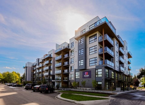 A modern apartment building with a parking lot in front.
