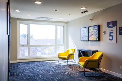 A room with a carpeted floor, two yellow chairs, and a poster with the number 5 on it.