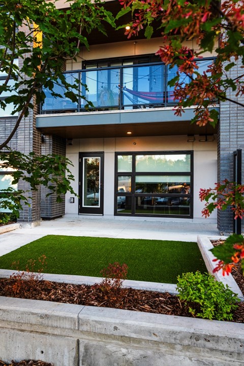 A modern house with a glass balcony and a green lawn.