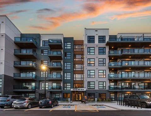 A modern apartment building with cars parked in front.