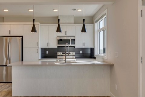 A modern kitchen with a white island and stainless steel appliances.