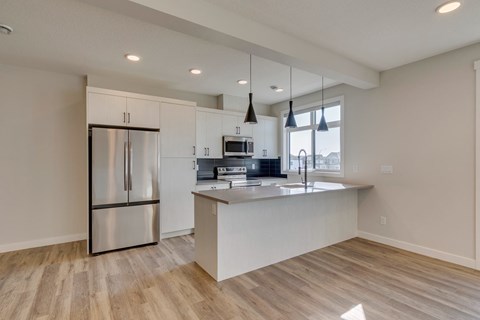 A modern kitchen with a refrigerator, microwave, and oven.