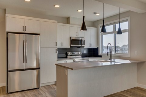 A modern kitchen with a stainless steel refrigerator and wooden cabinets.