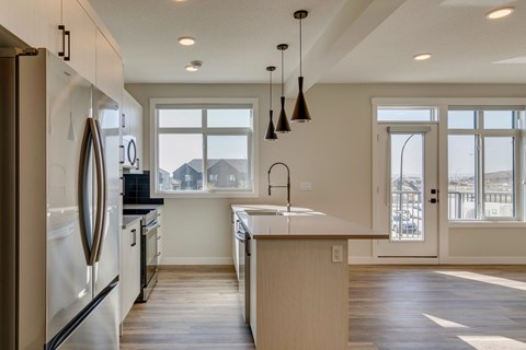 A modern kitchen with a large island and pendant lights.