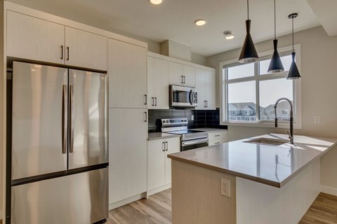 A modern kitchen with a stainless steel refrigerator and a central island.