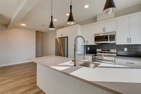 A modern kitchen with a stainless steel refrigerator and a sink.