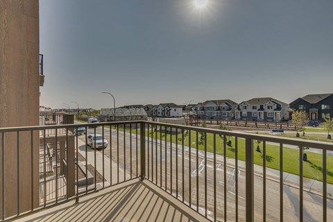 A balcony overlooks a street with cars and houses.