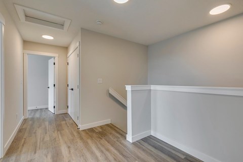 A hallway with a wooden floor and white walls.