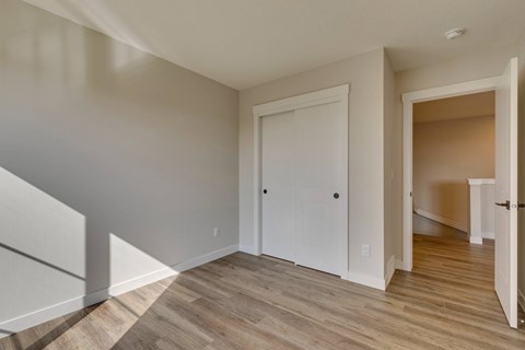 A room with a white door and wooden flooring.
