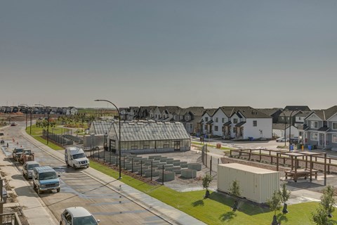 A street view of a residential area with houses, cars, and a construction site.