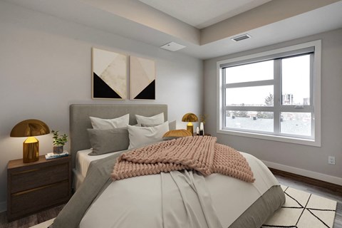 A bedroom with a large bed, a nightstand with a lamp, and a window showing a view of a street.