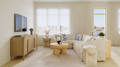A living room with a white couch, a wooden table, and a television.