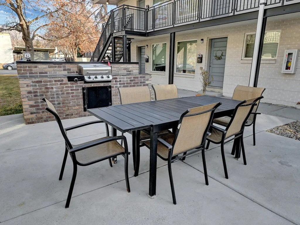a patio with a table and chairs and a grill