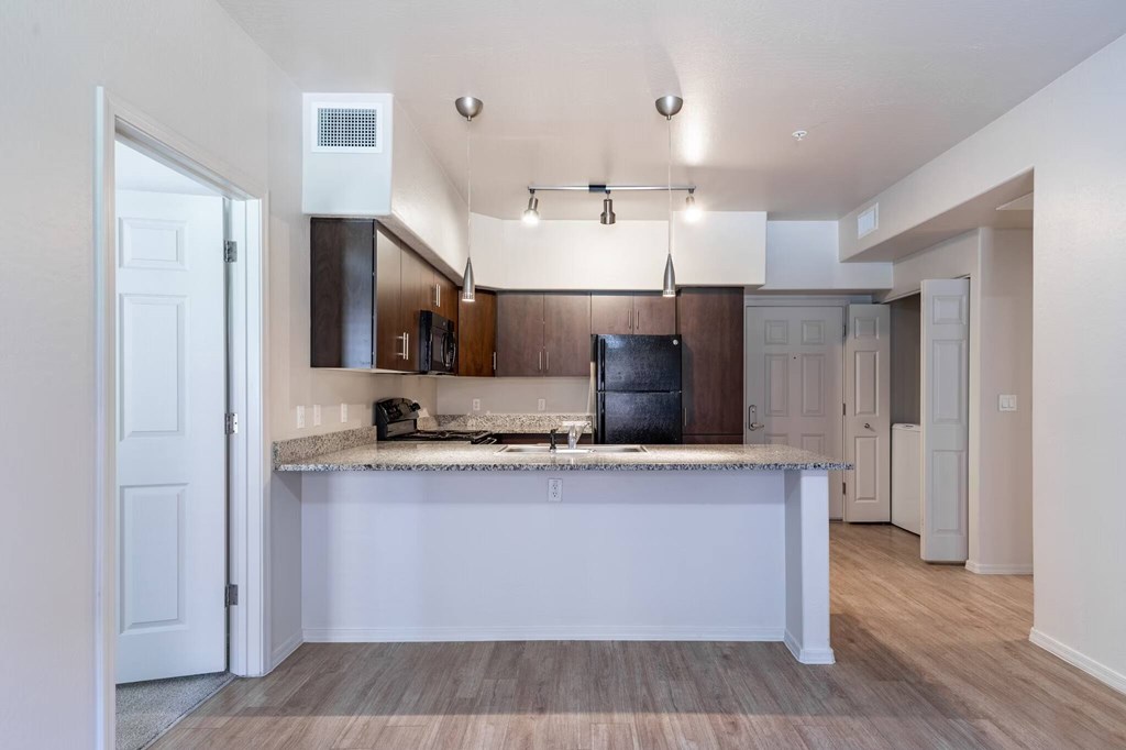 A kitchen with a white island and a black refrigerator.
