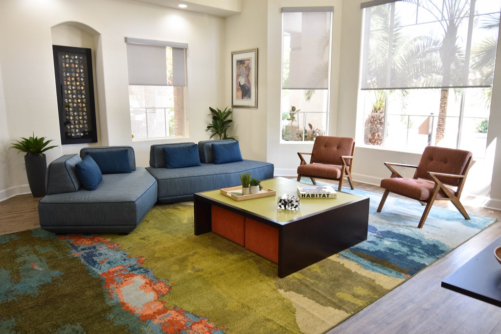 Clubhouse seating area with navy blue sofas and coffee table on colorful area rug in center of room