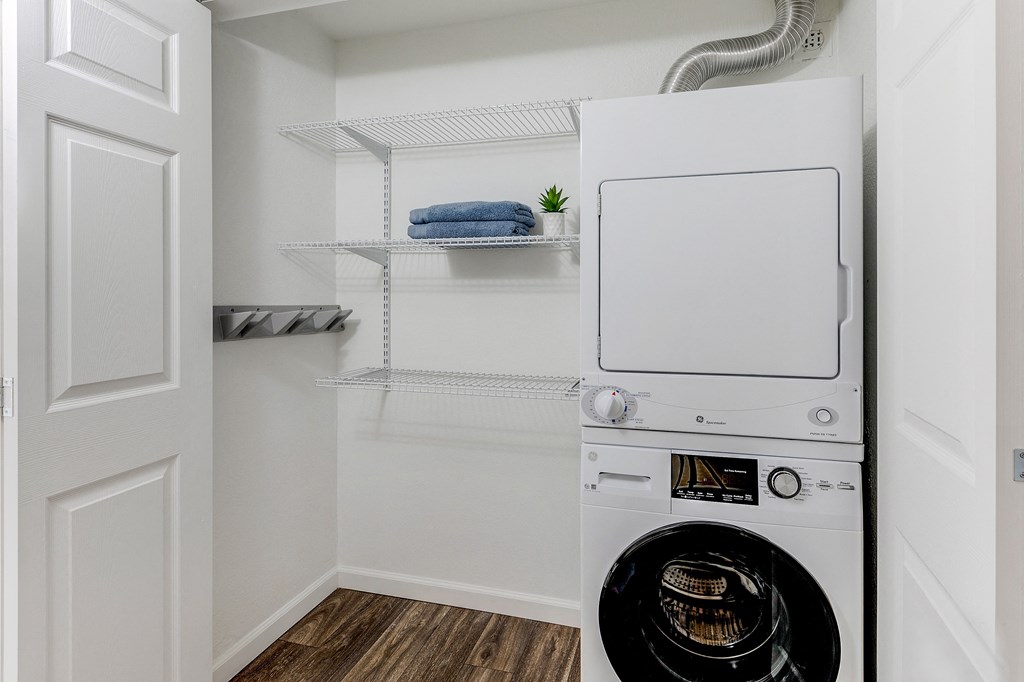 a small laundry room with a washer and dryer and a closet with shelves at Stonebridge, Phoenix, AZ, 85032