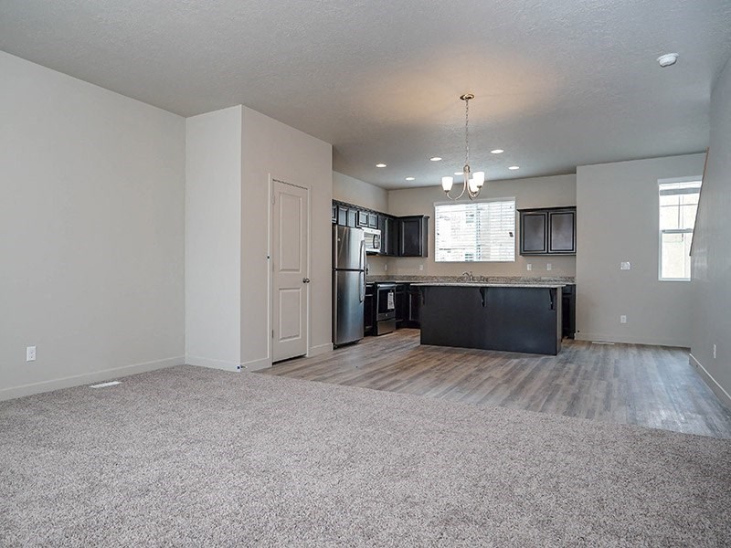 an empty living room and kitchen with a refrigerator