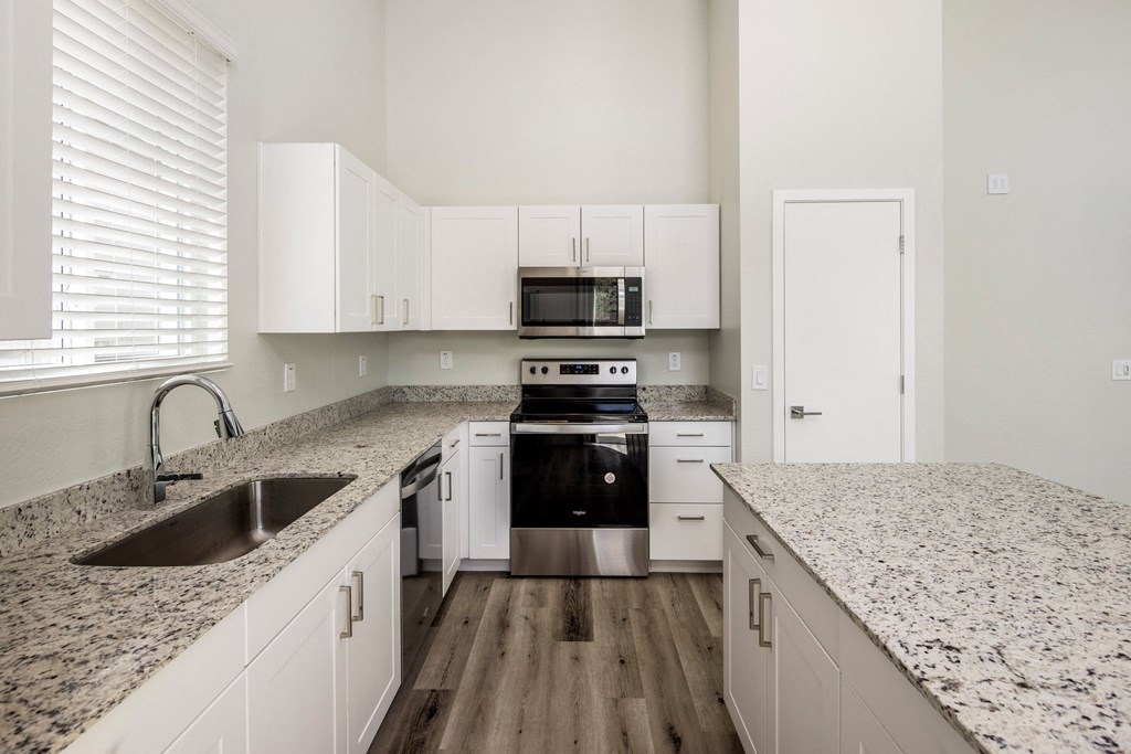 a kitchen with white cabinets and a granite counter top