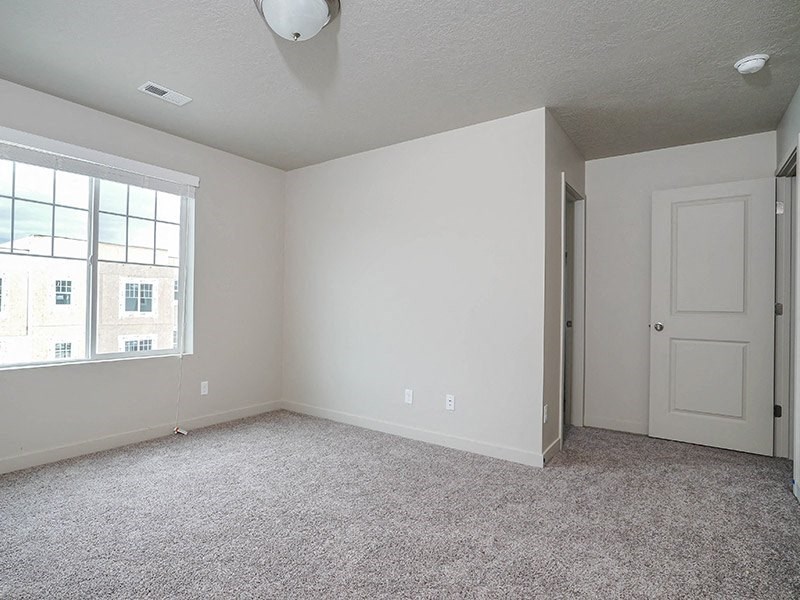 an empty living room with a white door and a window