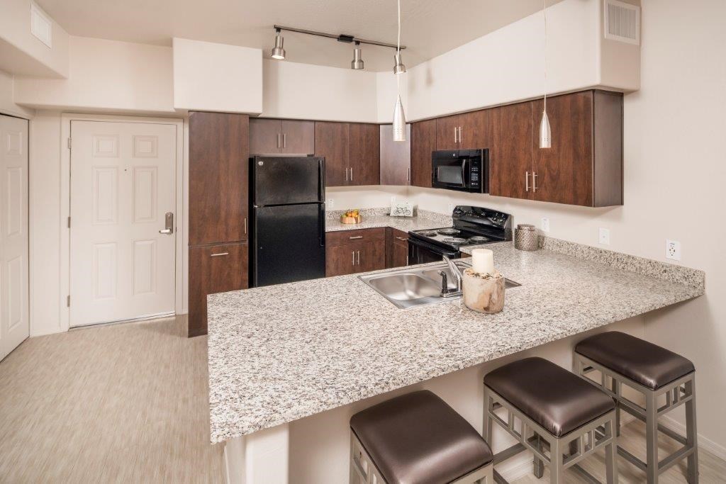 A kitchen with a granite countertop and stainless steel appliances.