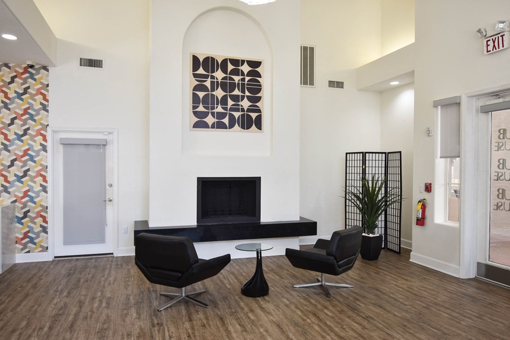 Modern black leather positioned on each side of small side table in front of fireplace. Modern art painting hangs above fireplace