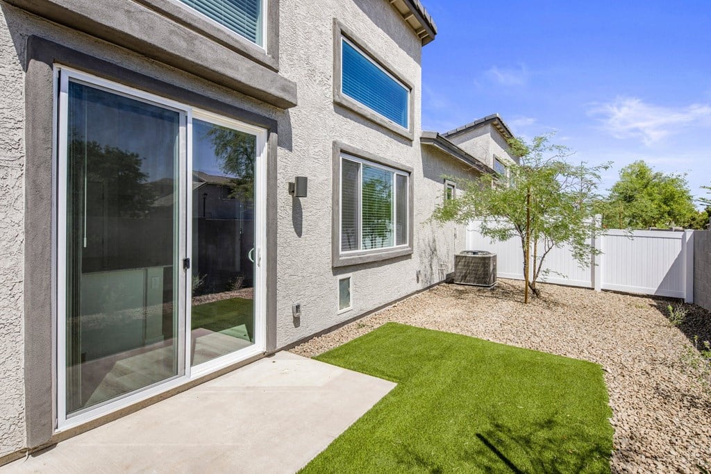 a backyard with a grassy area and a patio with a tree