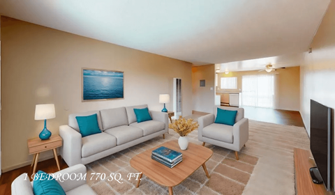 A living room with a white couch, a blue pillow, a wooden coffee table, and a painting on the wall.