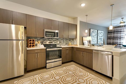 A modern kitchen with a stainless steel refrigerator and a patterned rug on the floor.