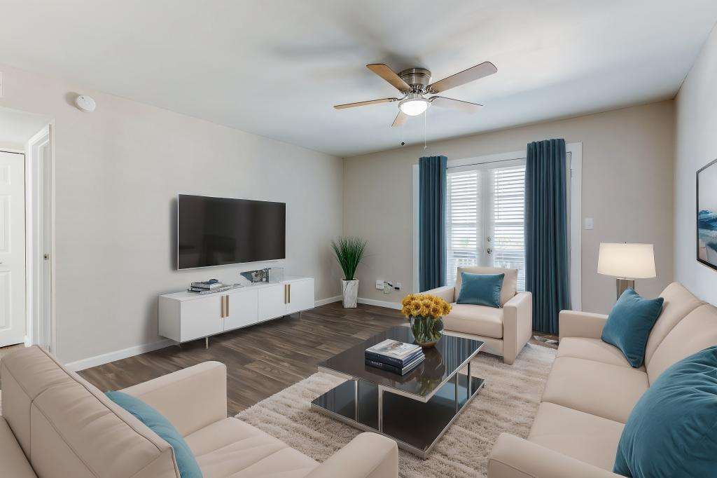 A living room with a white couch, a coffee table, and a flat screen TV mounted on the wall. at Stonebridge, Phoenix, AZ, 85032