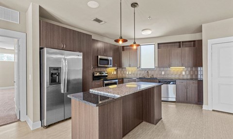A modern kitchen with a refrigerator, microwave, and oven.