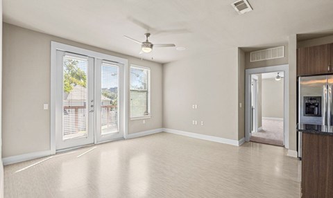 A spacious living room with a ceiling fan and sliding glass doors.