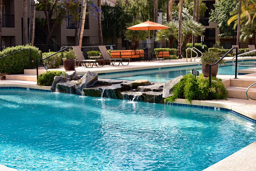 Pool View 2 Water flowing over water feature from heated lap pool into second pool area surrounded by lush mature landscaping and poolside seating