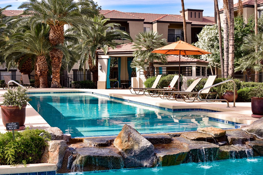 resort-style  surrounded by poolside chaise lounge chairs, large palm trees