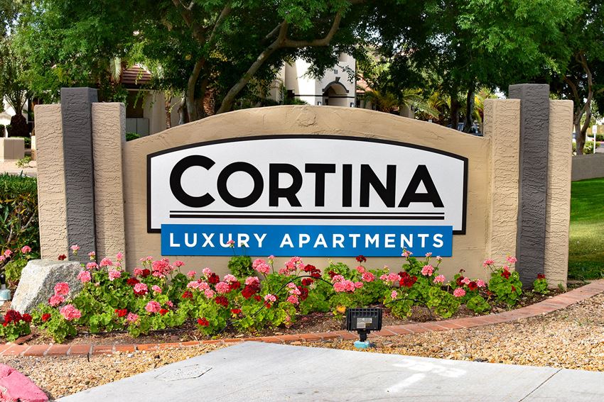 Signage reading Cortina Luxury Apartments with orange and red flowers planted in garden in front of sign - Photo Gallery 1