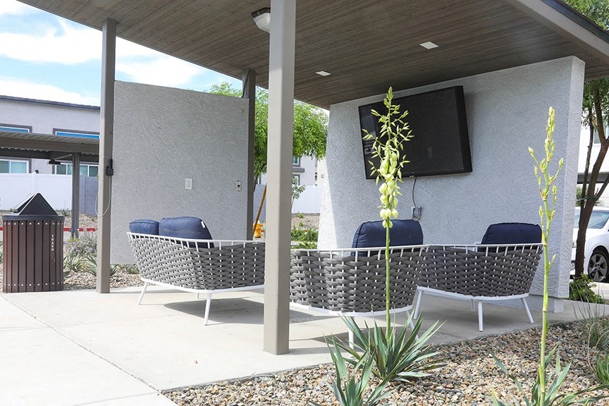 a patio with two chairs and a tv under a roof