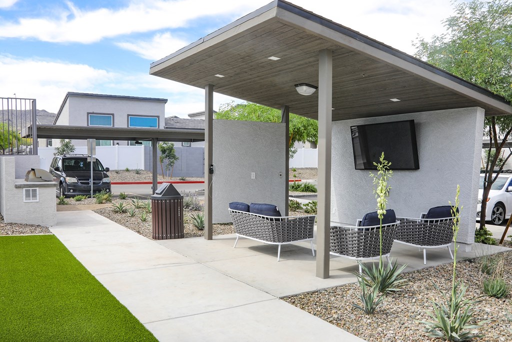 a patio with chairs and a television on the side of a house