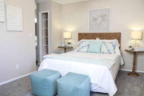 a bedroom with a bed and two stools in front of it