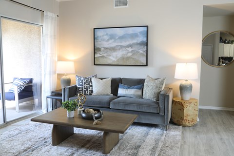 A living room with a grey couch, a coffee table, and a painting on the wall.