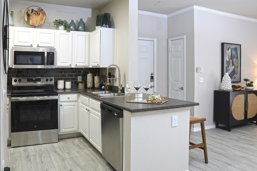 A kitchen with white cabinets and a black countertop.