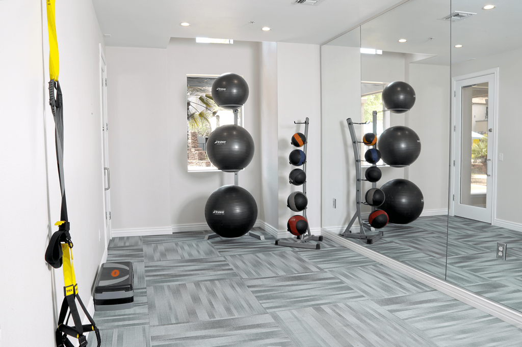 A room with a grey carpet and a yellow exercise equipment.