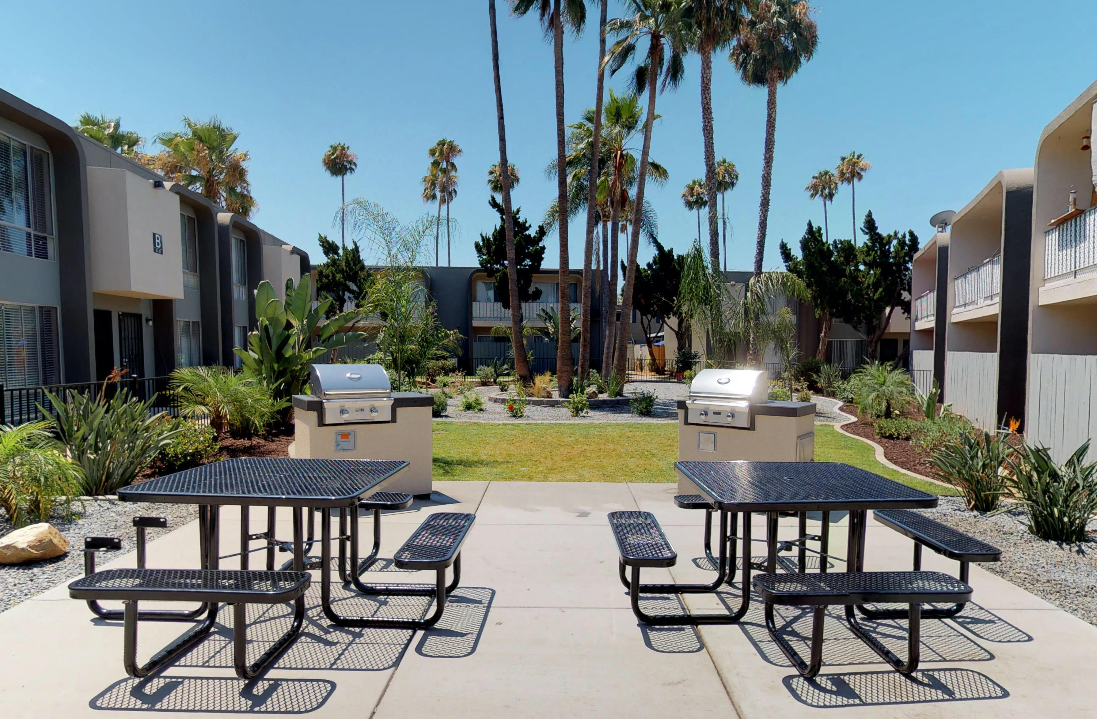 a patio with picnic tables and barbecue grills