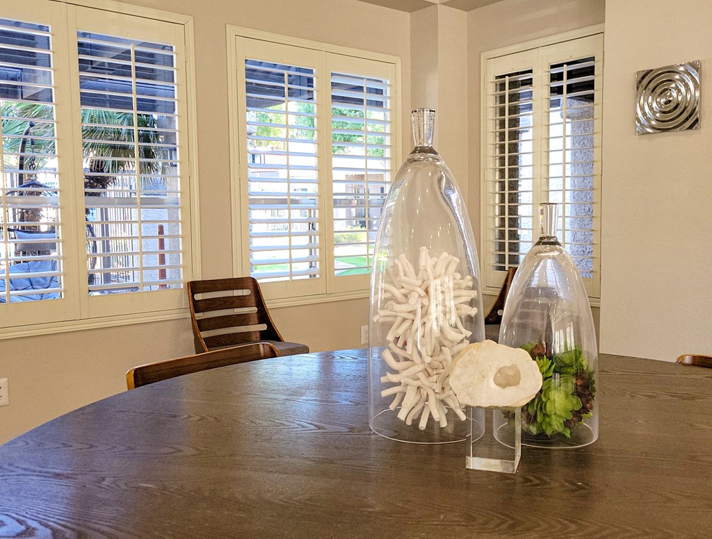 Big round wooden table in the community center with windows showing the common areas of community
