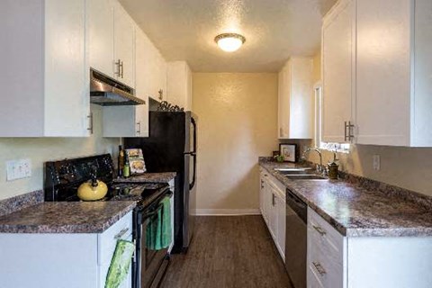 a kitchen with marble counter tops and a black refrigerator