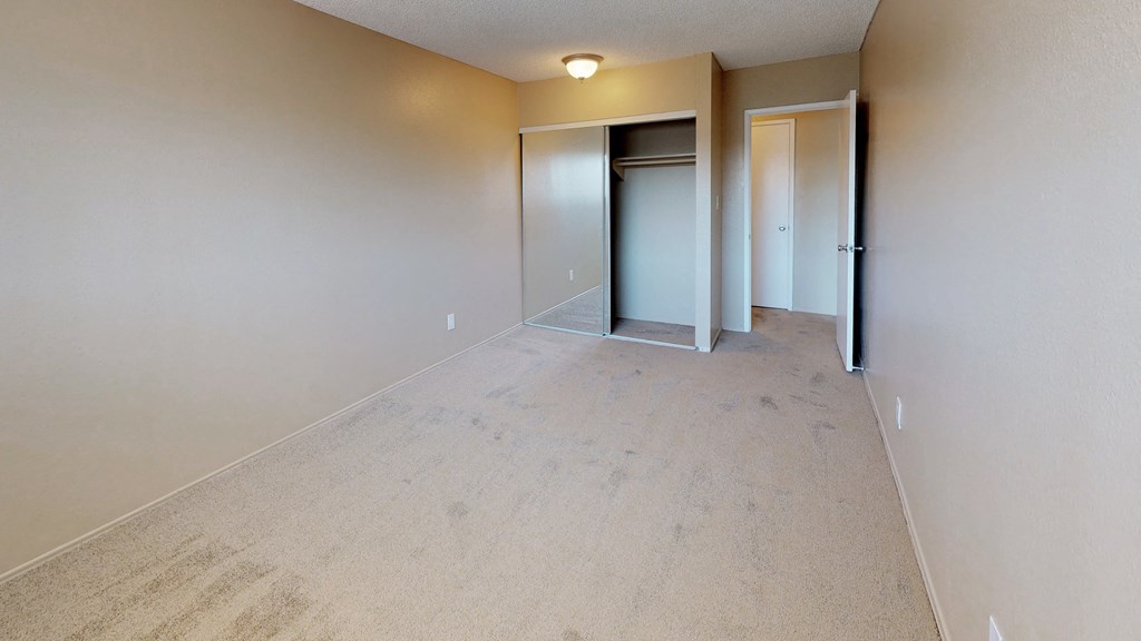 an empty room with a hallway and a door to a closet