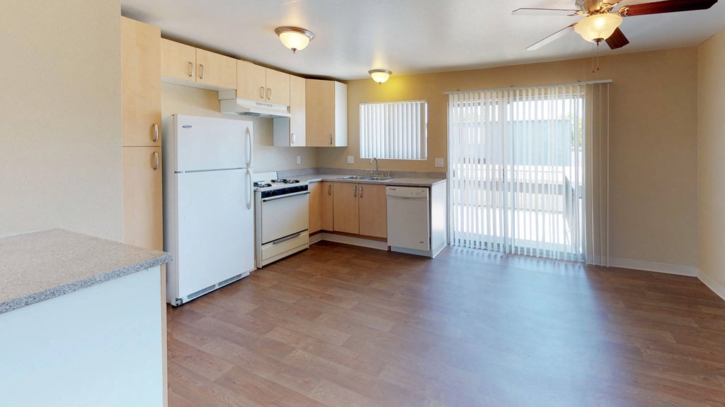 an empty kitchen with white appliances and wood floors
