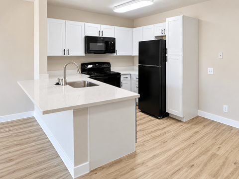 A kitchen with black appliances and white cabinets.