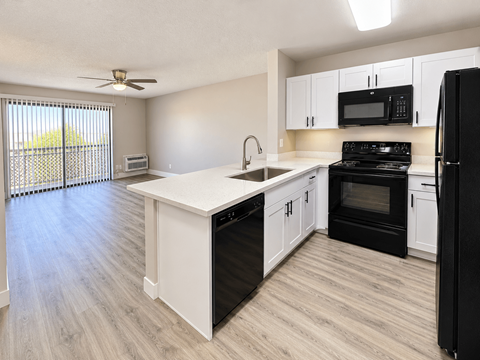 A kitchen with black appliances and white cabinets.