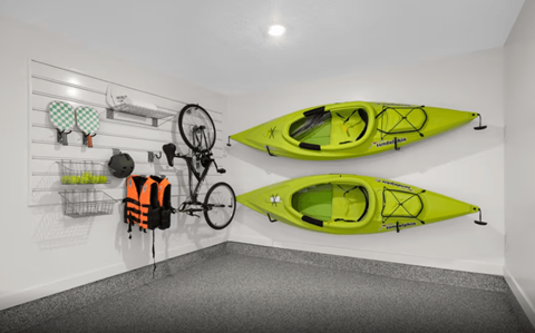 A room with a bicycle, two kayaks, and a shelf with various items.