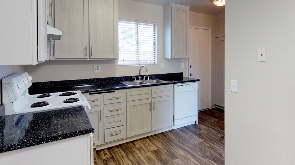 an empty kitchen with white cabinets and black counter tops