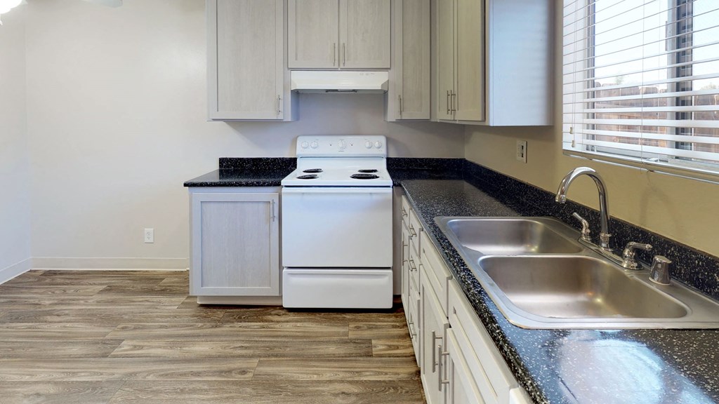 an empty kitchen with white appliances and a counter top and a sink